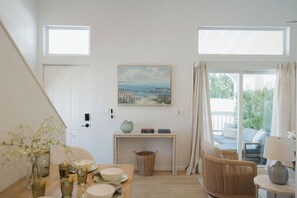 Una habitación con comedor, chimenea, una silla de mimbre y vistas a través de un ventanal.