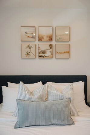 Ein Schlafzimmer mit einem Bett, Kissen und sechs gerahmten Bildern an der Wand.