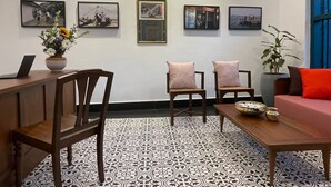 A modern hotel lobby with a tiled floor, wooden furniture, and artwork on the walls.