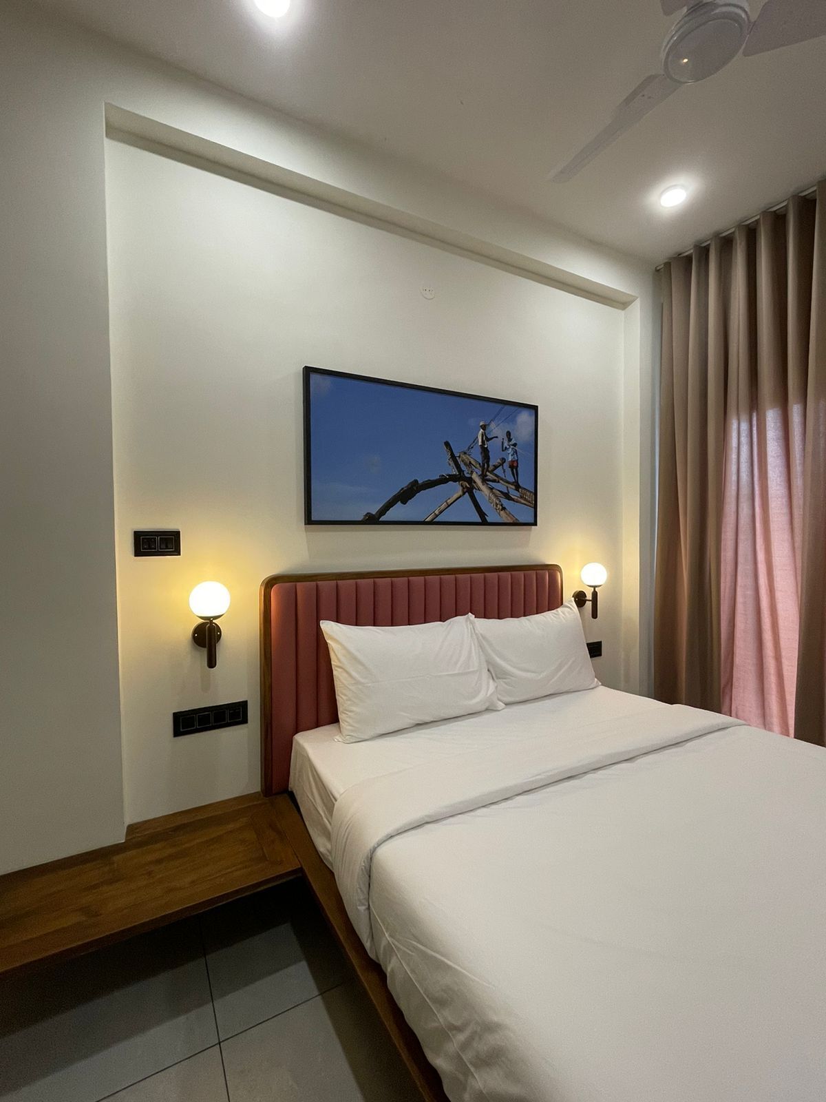 A hotel room with a bed, a nightstand, a wall-mounted TV, and a ceiling fan.