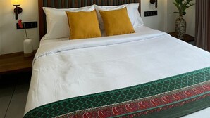 A hotel room with a large bed, two bedside lamps, a wall-mounted picture, and a vase with flowers.