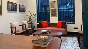A cozy living room with a wooden coffee table, a sofa with red cushions, and a bookshelf.