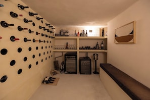 A wine cellar with wine racks, shelves, and a wine cooler. - Exomitis1 Cellar & Sea Escape (8CMR+3XX Exomitis, Greece)