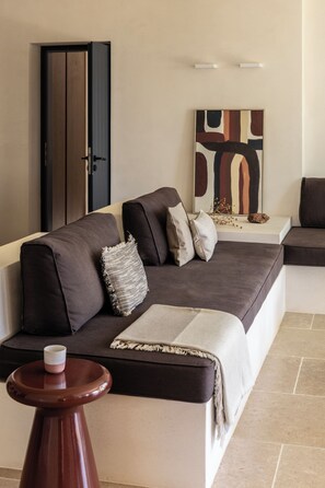 A modern living room with a sofa, a small table, and a door. - Exomitis1 Cellar & Sea Escape (8CMR+3XX Exomitis, Greece)