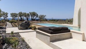 Zona de piscina con área de estar integrada, vista despejada al mar y jardín ajardinado.
