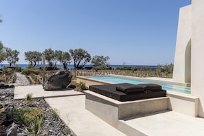 A poolside area with a built-in seating area, a clear view of the sea, and a landscaped garden. - Exomitis1 Cellar & Sea Escape (8CMR+3XX Exomitis, Greece)