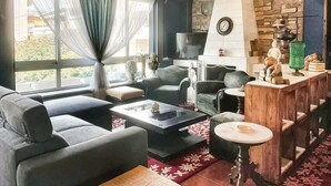 A living room with a sofa, chairs, a coffee table, a fireplace, and a stone wall.