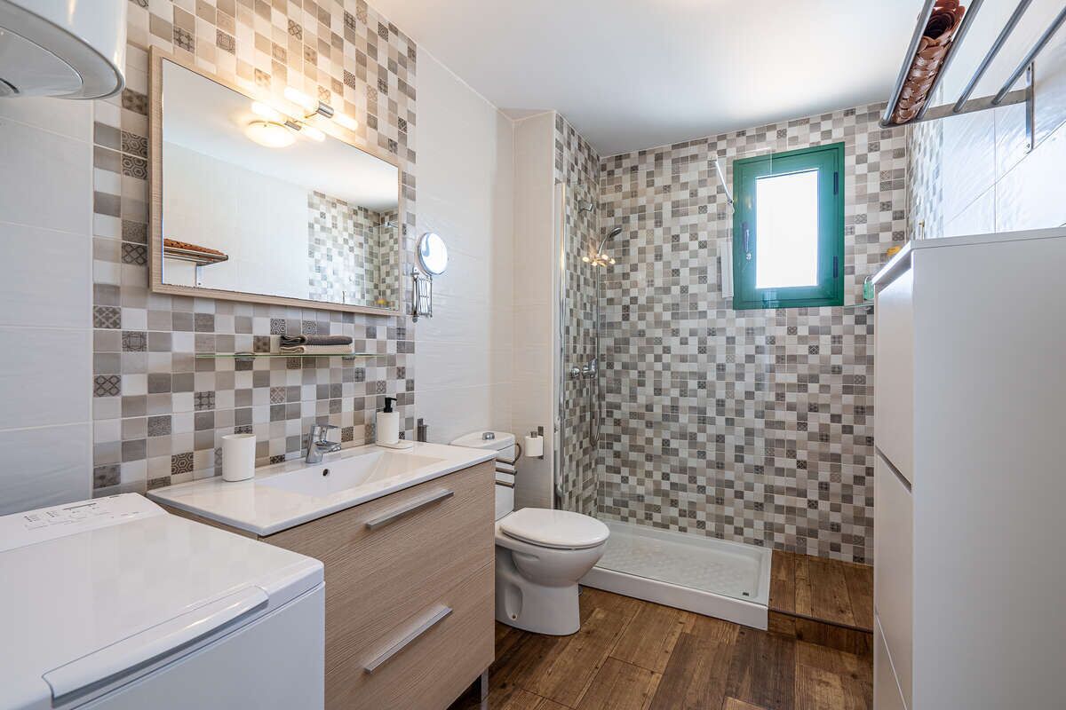 Une salle de bain avec douche, toilettes et lavabo.