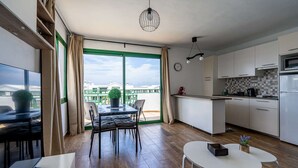 Una cocina moderna con armarios blancos, un microondas y un ventanal grande.