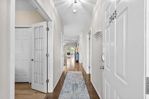 A hallway with white doors, a blue patterned rug, and a ceiling light fixture. - 3 bedroom in gated community. Walk to the beach. (North Myrtle Beach)