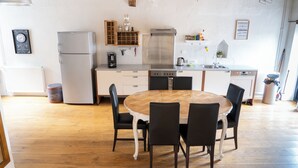 Una cocina con refrigerador, estufa, lavabo y mesa de comedor con sillas.