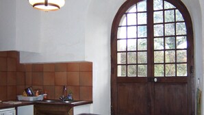 A kitchen with a large wooden table, a built-in oven, and a window with a wooden door. - demi-château de Paulignan for 15 people (TRAUSSE)