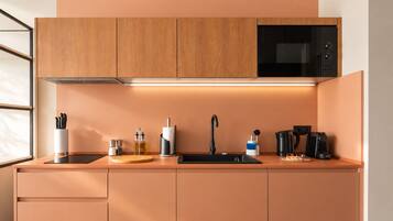 A modern kitchen with wooden cabinets, a black microwave, a sink, and various appliances.