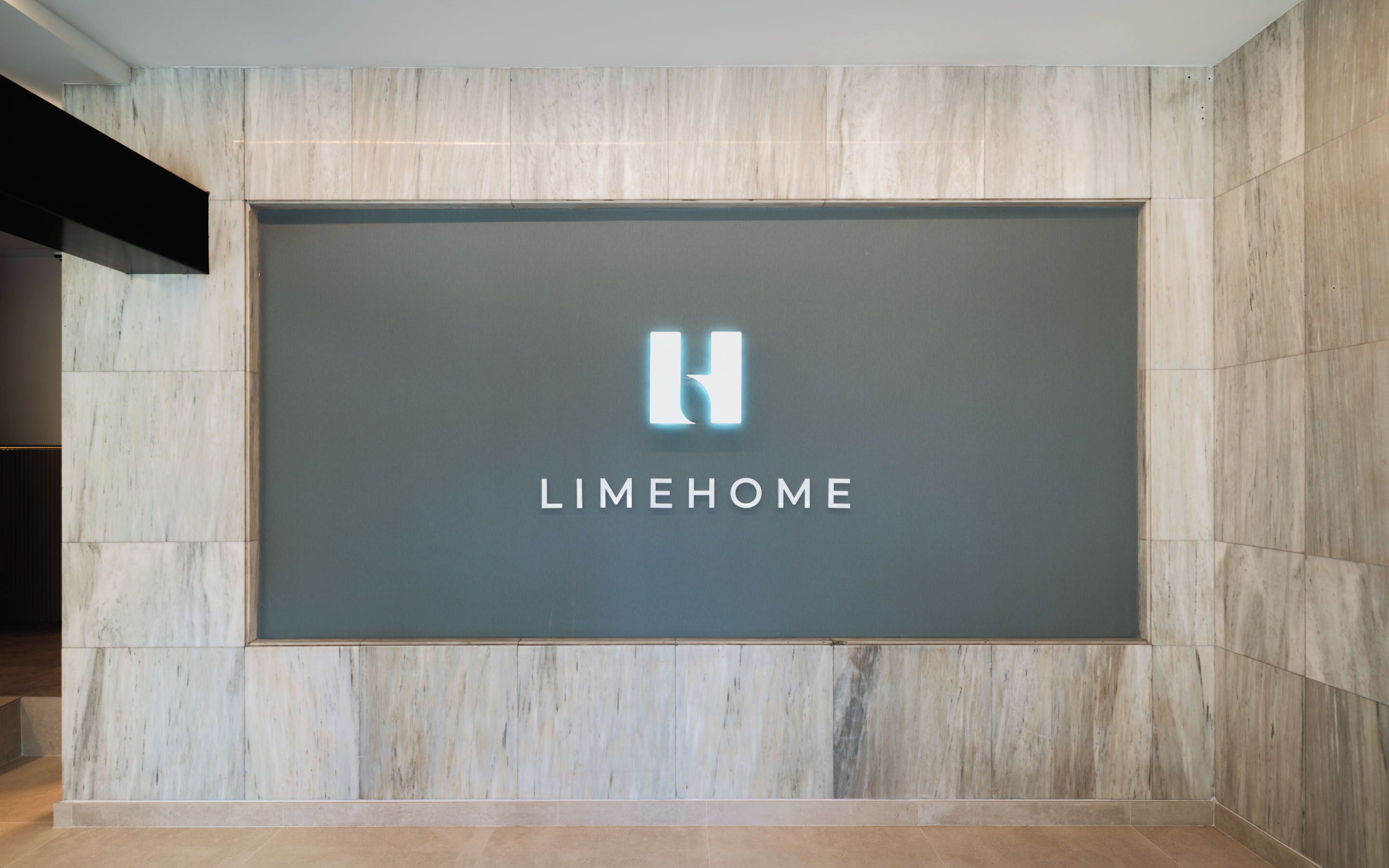 Eine Wand mit einem großen Schild, das das 'LIMEHOME'-Logo und den Schriftzug zeigt.