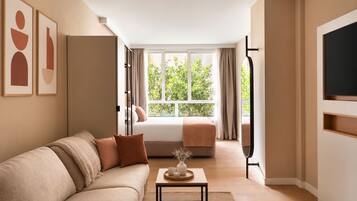 A modern living room with a sofa, a coffee table, and a view of a balcony with plants.