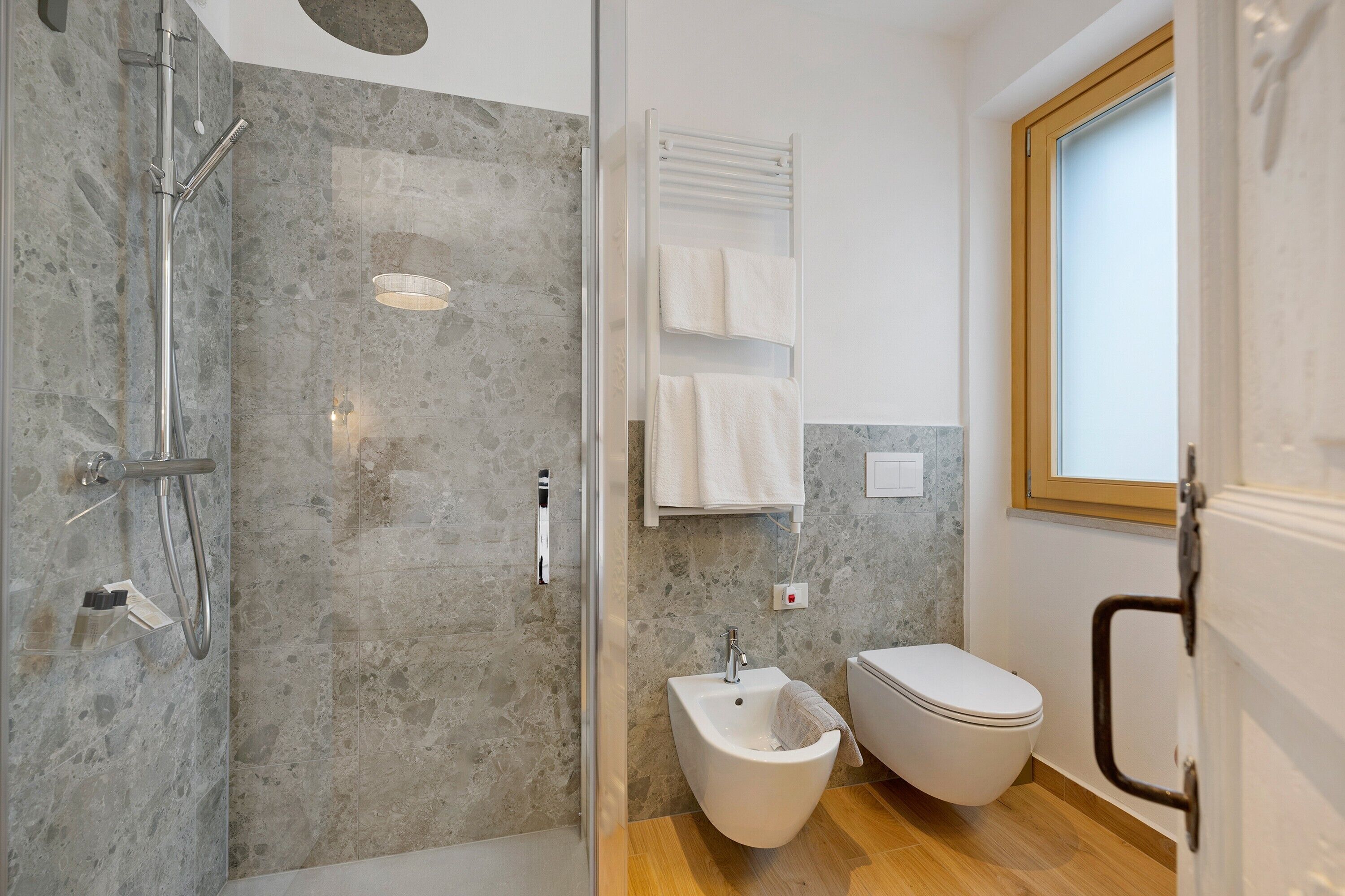 Une salle de bain moderne équipée d’une douche, d’un bidet, de toilettes et d’une fenêtre.