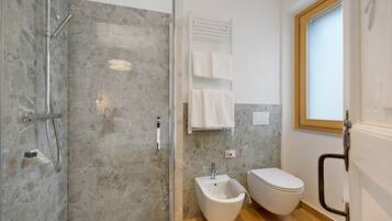 Une salle de bain moderne équipée d’une douche, d’un bidet, de toilettes et d’une fenêtre.