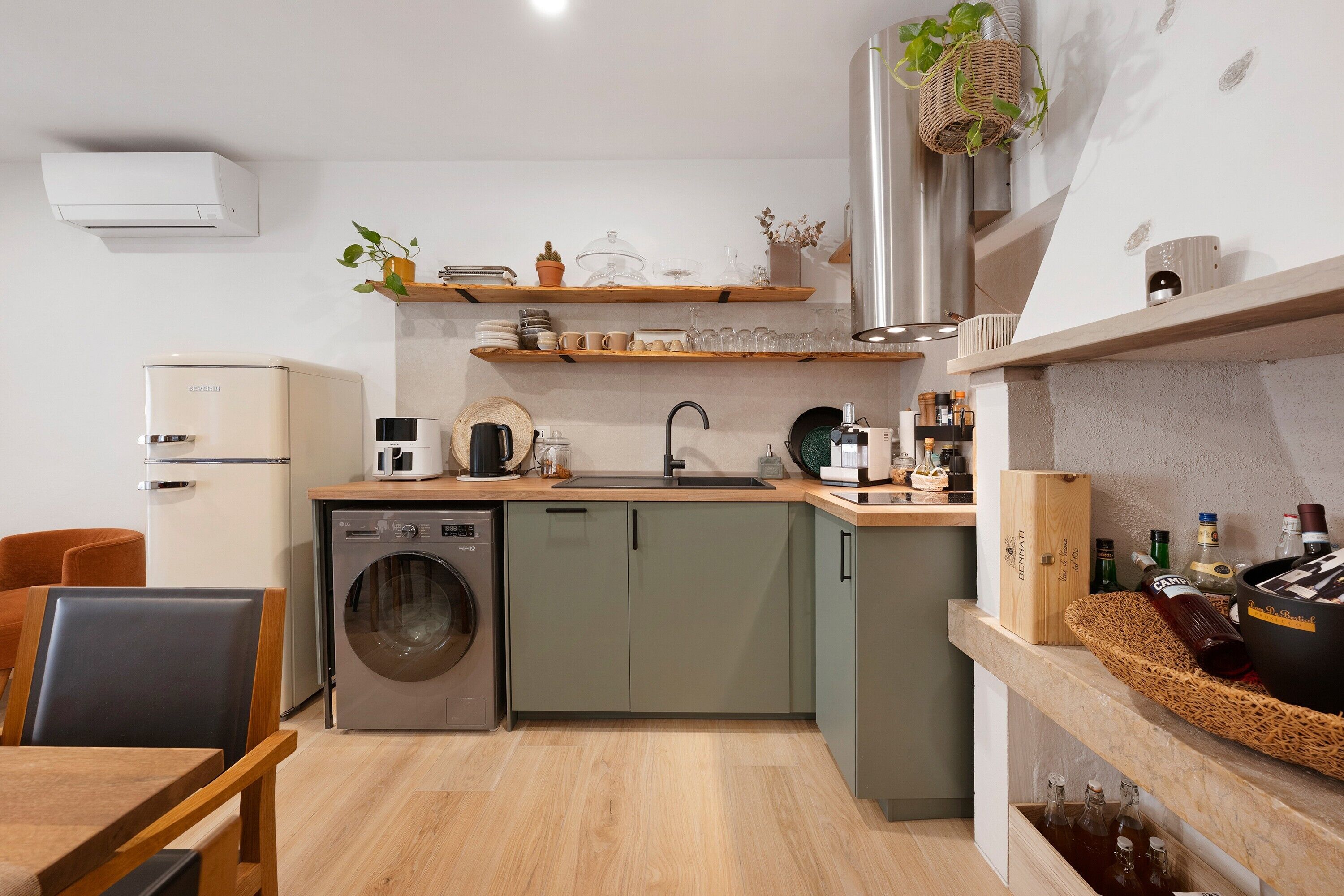 Une cuisine compacte équipée d’un lave-linge, d’un évier et d’une machine à café.