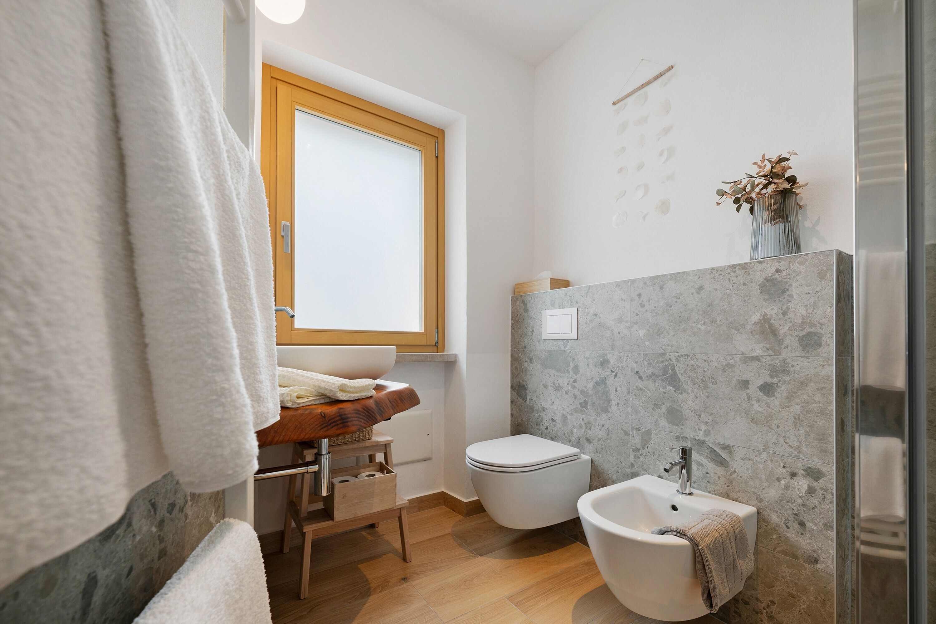 Ein Badezimmer mit einem Holzwaschtisch, einem weißen Waschbecken, einer Toilette, einem Bidet und einer Duschkabine.