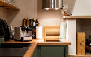 A kitchen with a coffee machine, wooden cutting board, and various bottles on the counter. - Homestay 'Residenza Tre Cuori' with Lake View, Wi-Fi and Air Conditioning (Torri del Benaco)