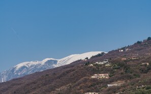 Un paysage montagneux, avec des sommets enneigés et des maisons éparpillées sur le flanc d’une colline.