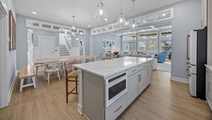 A spacious kitchen with a large island, white cabinetry, and pendant lighting. - BRAND NEW Saltaire 8 Bedroom Luxury Home at Water Oak (Kill Devil Hills)