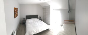 Une chambre à coucher avec un lit, des tables de chevet, une lampe, un radiateur et une fenêtre.