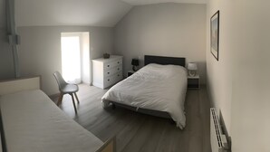 A bedroom with a bed, a desk, a chair, a dresser, and a bedside table with a lamp. - Vacation Rental in Beauvoir with Wi-Fi, Family-Friendly, Pets Welcome (Beauvoir)