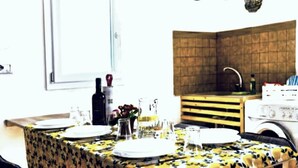 A dining area with a table set for four, a kitchen area with a wooden counter, and a window with a view. - The Attic on the Green (Sicilia)