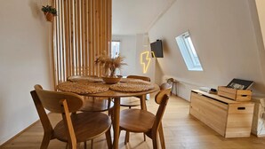 A dining area with a round wooden table, woven placemats, and wooden chairs. - Appartement Lumineux Scandinave - Coup de Foudre (Arras)
