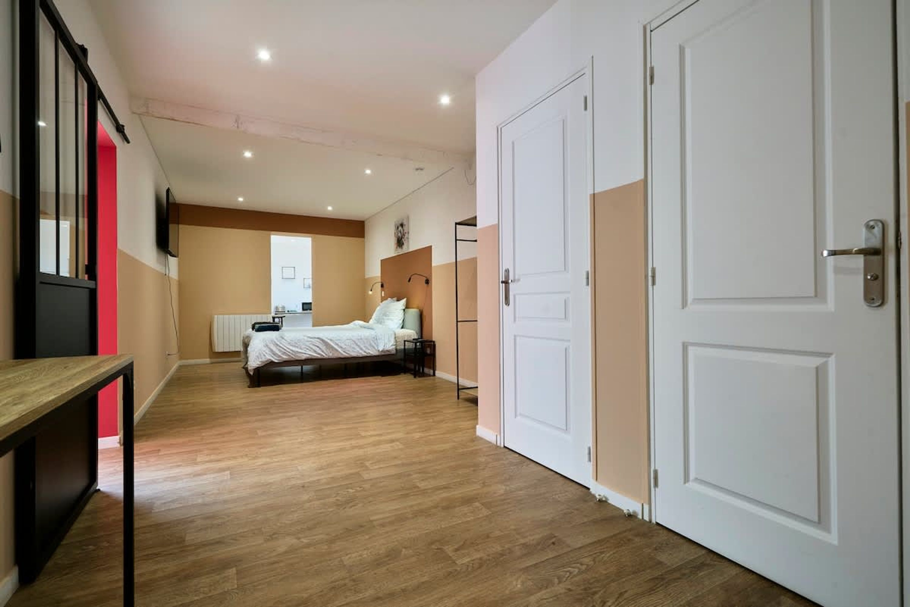 Ein Hotelzimmer mit Bett, Schreibtisch, Heizkörper und Tür.