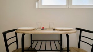 Ein Esstisch mit zwei Stühlen, ein Fenster darüber und ein kleines dekoratives Objekt auf dem Tisch.
