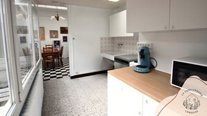 Eine Küche mit kariertem Boden, einer Kaffeemaschine und einem Essbereich mit Stühlen und Tisch.