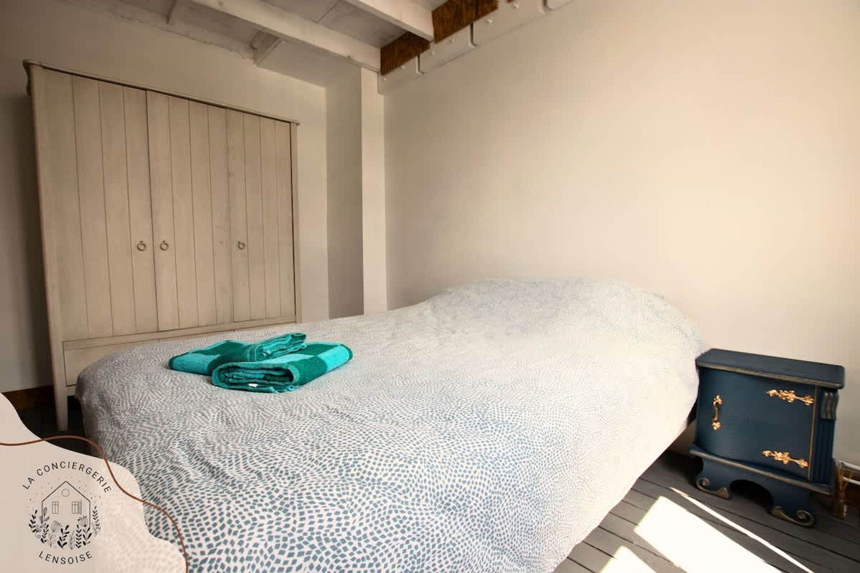 Une chambre à coucher avec un lit, une armoire et une petite commode.