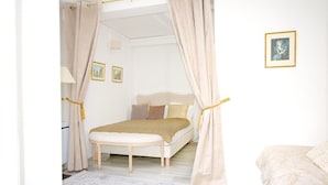 Ein Schlafzimmer mit einem Bett, einer Bank und einem Vorhang.