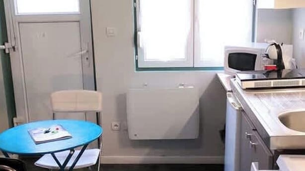 Uma cozinha compacta com uma pequena mesa de jantar, micro-ondas e pia.