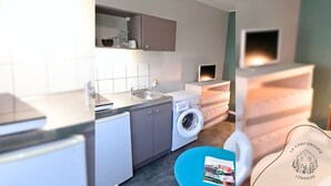 Cozinha compacta com máquina de lavar, pia e bancada pequena.