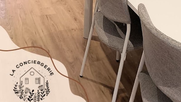 A modern living room with a sofa, a dining table with chairs, a small round table with a plant, and a door. - Le Cantin 4 Pers Wifi Courette Bollaert (Lens)
