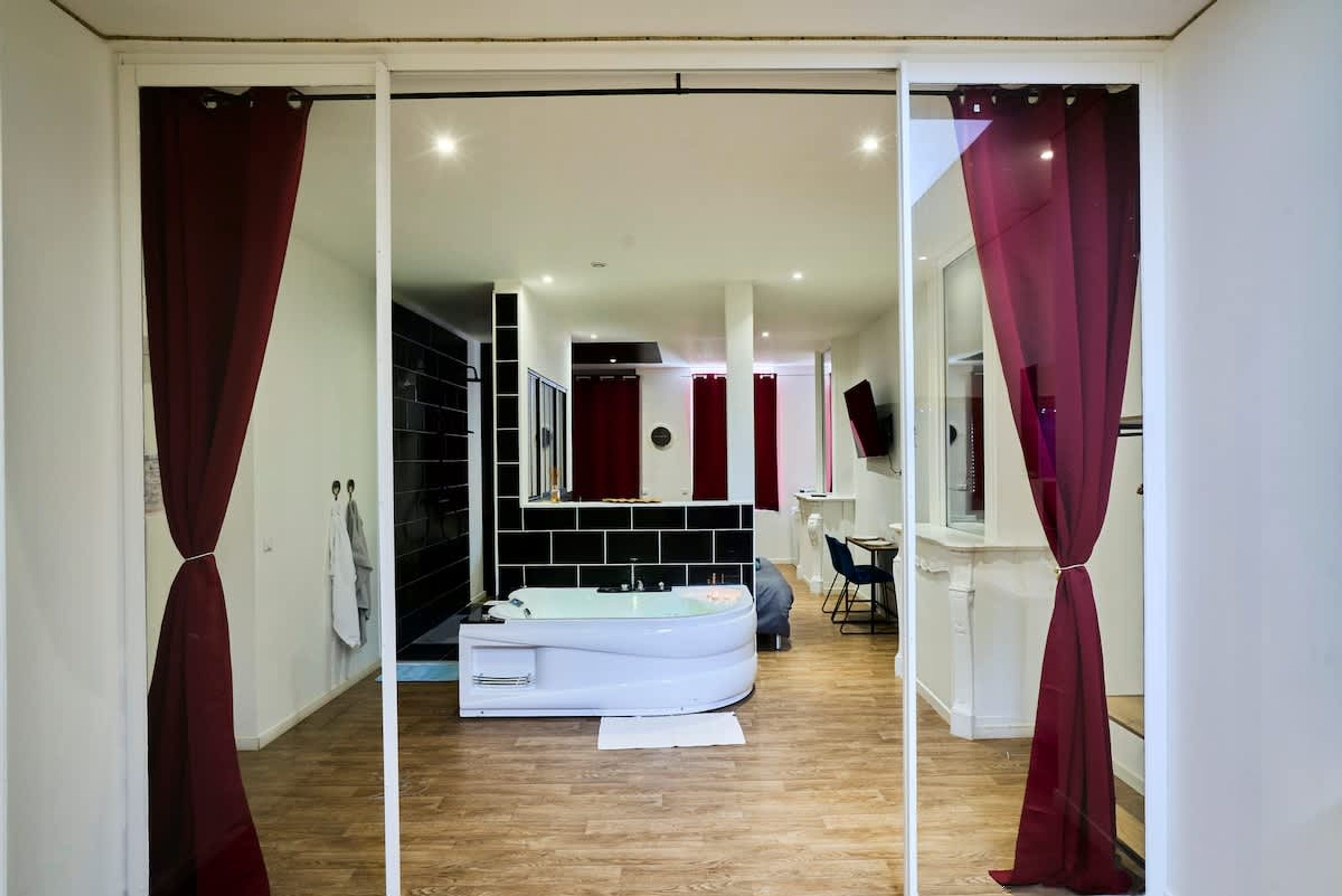 Un baño moderno con una bañera blanca, un espejo y cortinas rojas.