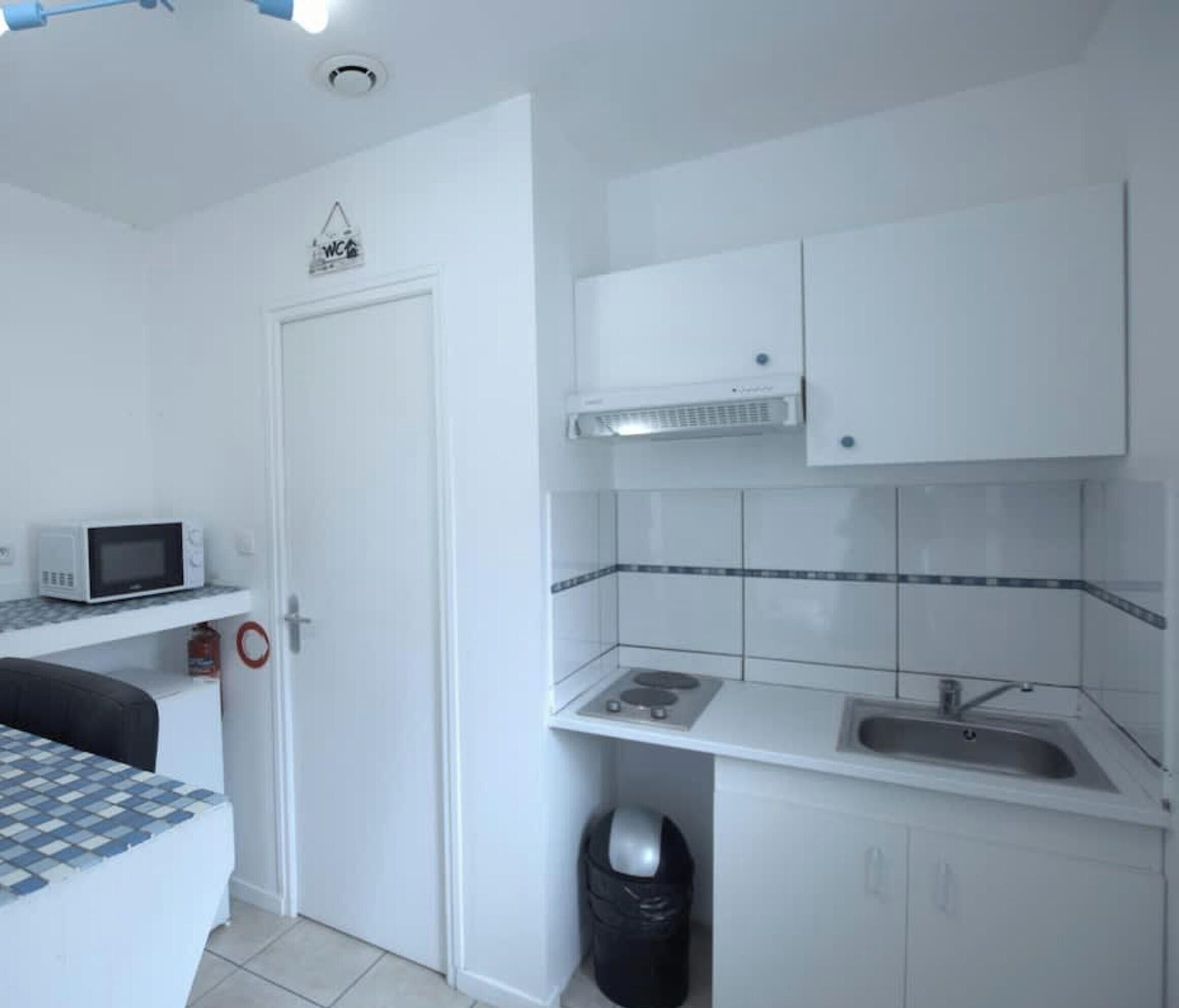 A compact kitchenette with a microwave, sink, and cabinets.
