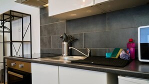 Eine moderne Küche mit einer Spüle aus Edelstahl, einem eingebauten Ofen und einer schwarzen Spritzschutzwand.