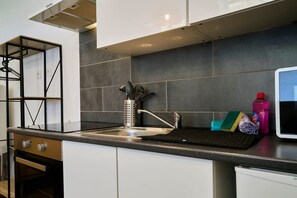 Eine moderne Küche mit einer Spüle aus Edelstahl, einem eingebauten Ofen und einer schwarzen Spritzschutzwand.