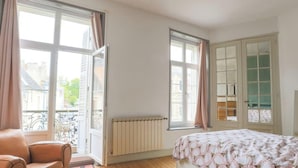 Une chambre à coucher avec un lit, un radiateur, une fenêtre donnant sur un beau paysage et une chaise.