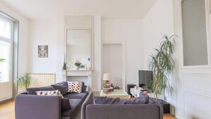 Un salon avec un canapé, une table basse, un téléviseur et une plante.