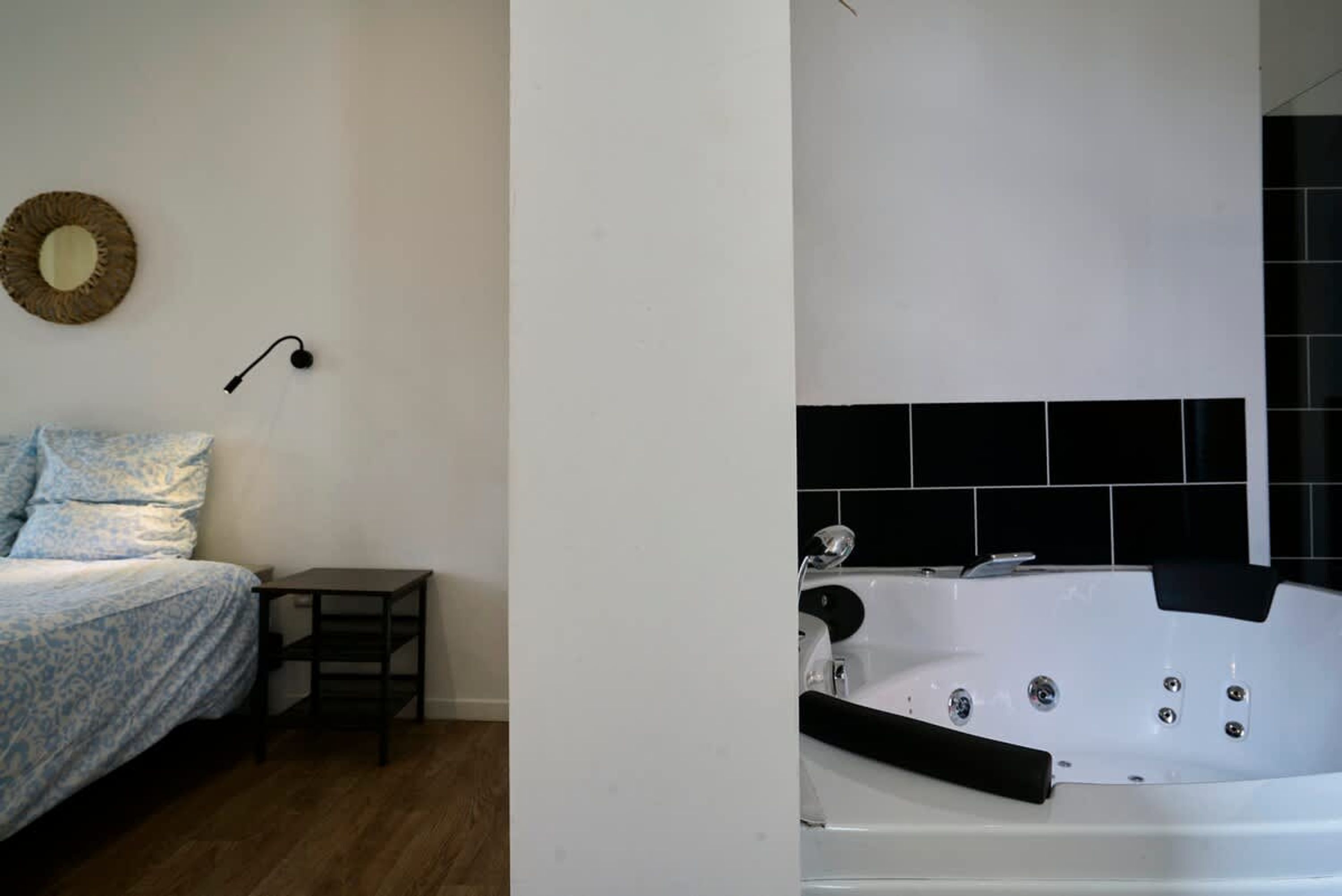 Une chambre à coucher avec un lit, une table de chevet et un miroir fixé au mur.