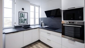 Een moderne keuken met een zwart aanrecht, roestvrijstalen apparatuur en een raam met uitzicht.