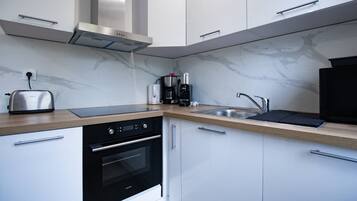 A modern kitchen with a built-in oven, a toaster, a coffee maker, and a sink.