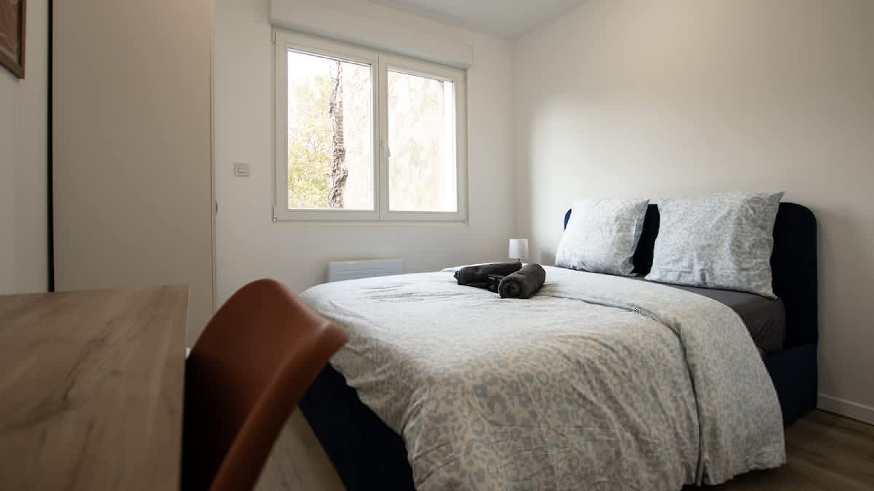 A bedroom with a bed, a chair, a window, and a radiator.