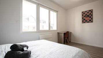 Un dormitorio con una cama, un escritorio y una silla.