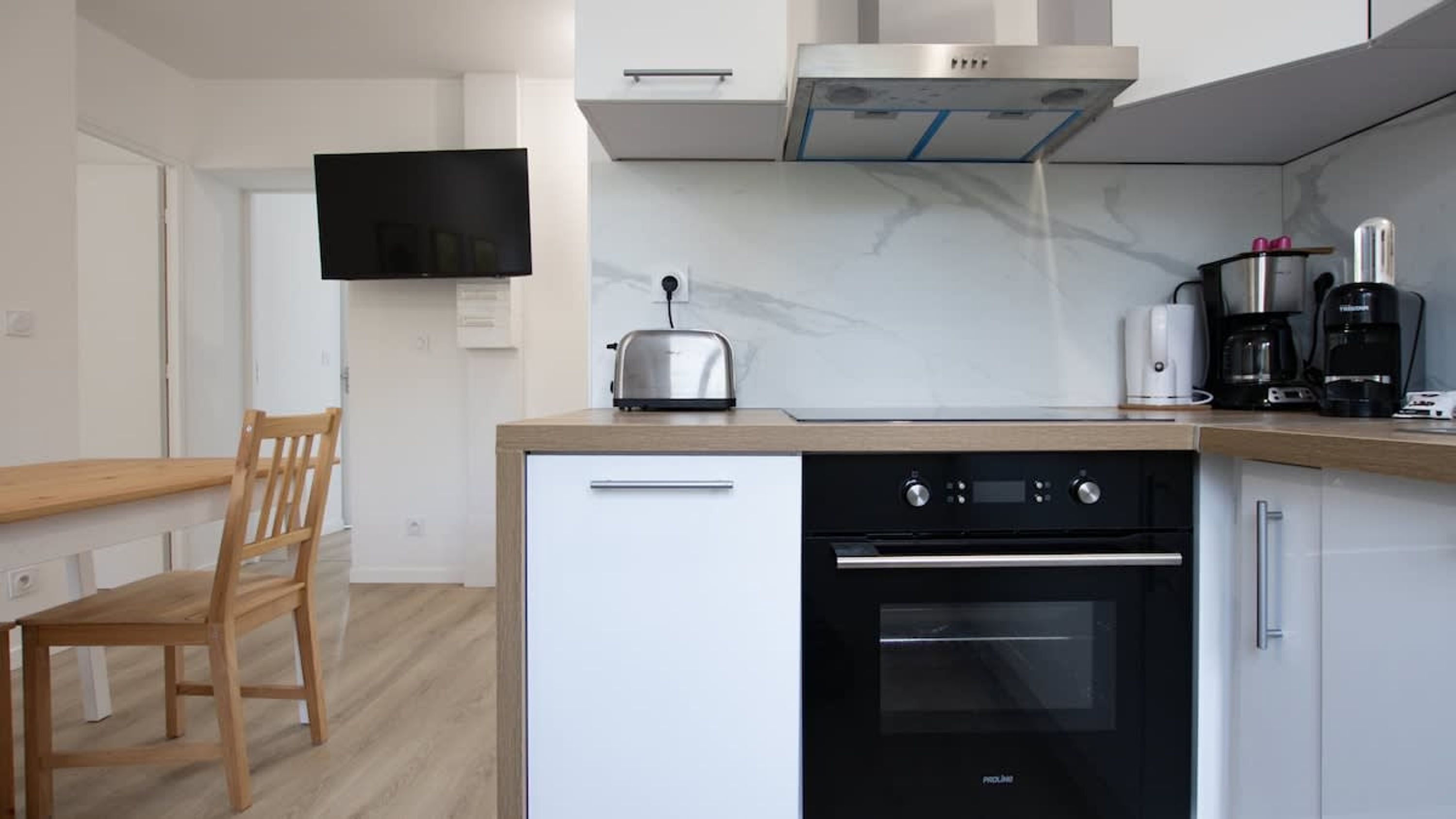 Eine kompakte Küche mit integriertem Ofen, Toaster und Kaffeemaschine auf der Arbeitsplatte.